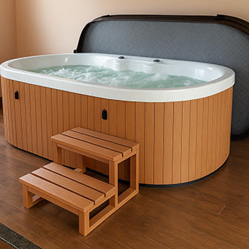 Oval wooden-sided hot tub with white interior and open cover on indoor wooden flooring.