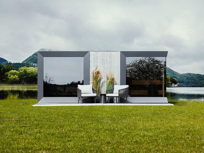 Genevas St. Moritz outdoor sauna with shower room set in lush green landscape with mountain views and misty skies.