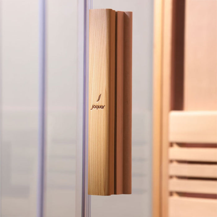 A beautifully crafted wooden handle on a glass door, engraved with the Jaquar logo, highlighting the sauna’s refined craftsmanship.