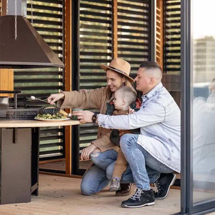 A couple enjoying their time grilling marshmallows at the built-in barbecue, showcasing the Garden Cube’s functionality for social gatherings.