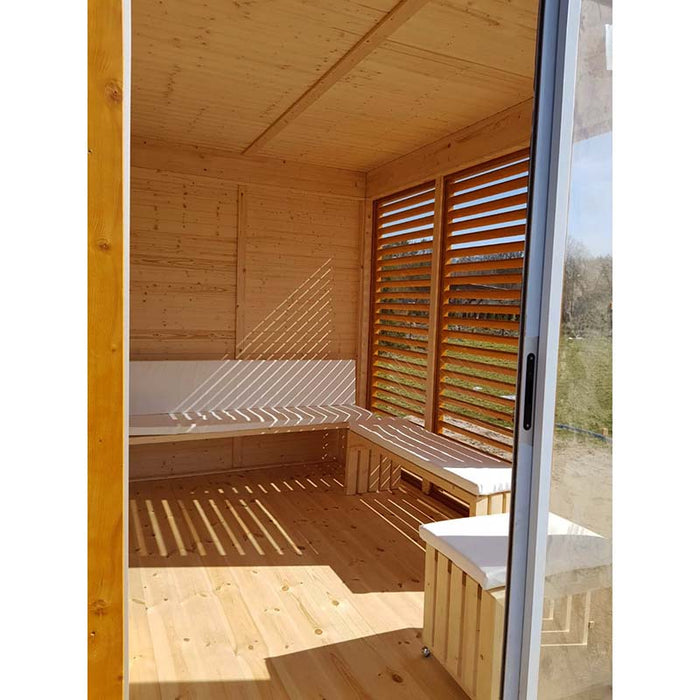 Main entrance of Sauna Cube 3 x 4m with with pillowed benches and windows in the background.