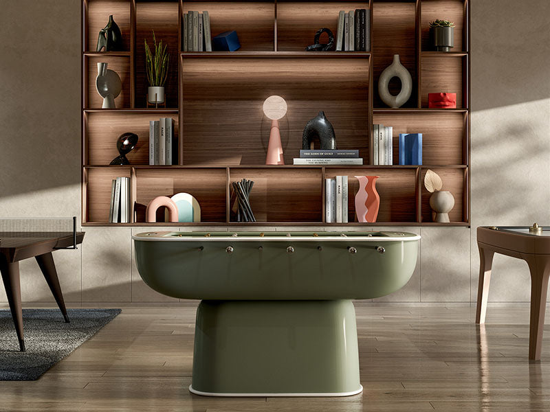 Elegant olive-green Oskar Foosball Table in a sophisticated living area featuring a wooden bookcase and curated modern art pieces.