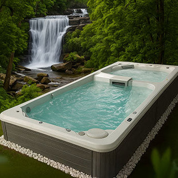 Acrylic swim spa in tropical forest setting with waterfall in background.