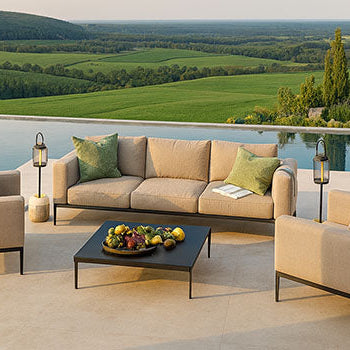 modern beige garden sofa set with black metal frame on a terrace overlooking an infinity pool and scenic countryside hills at sunset.