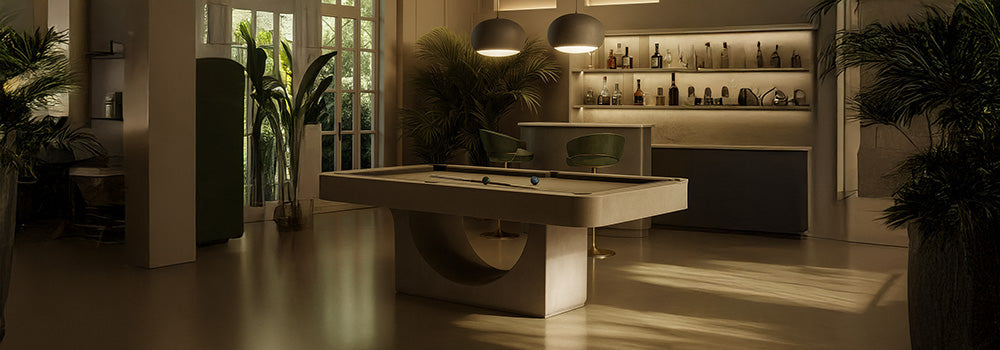 modern beige pool table in a softly lit luxury room with arched window, pendant lights, and home bar.