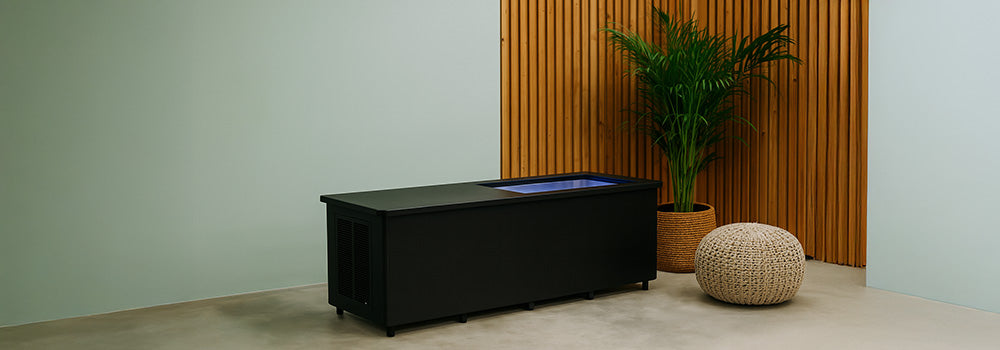 Sleek commercial ice bath with LED lighting in a stylish spa room with wood paneling and greenery.