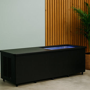 Sleek commercial ice bath with LED lighting in a stylish spa room with wood paneling and greenery.