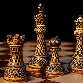 Ornate black and gold chess pieces on a red and cream checkered board with dark background.