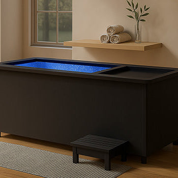 Modern black ice bath in elegant bathroom with wood floors and pendant lighting.