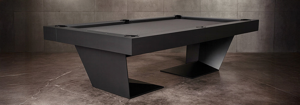 matte black modern pool table in an industrial-style room with concrete walls and floor.