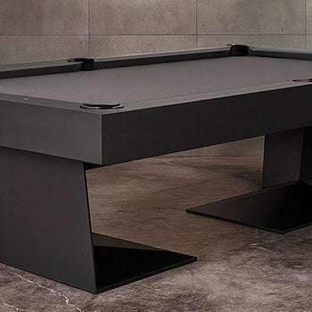 matte black modern pool table in an industrial-style room with concrete walls and floor.