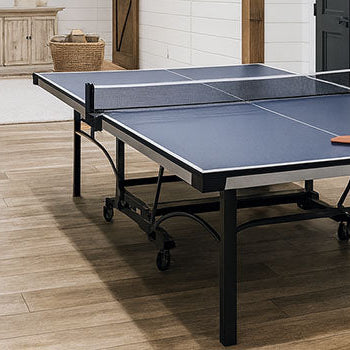 blue ping pong table in a stylish farmhouse basement with wood beams, shiplap walls, and modern black accents.