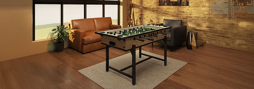Classic foosball table in a warm industrial loft with exposed brick walls, leather sofa, and large windows.