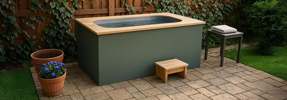 Minimalist cold plunge tub with wood top on a stone patio, surrounded by ivy-covered fencing and garden accents.