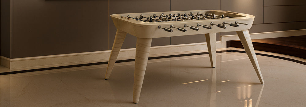 Elegant cream-colored foosball table in a luxurious modern room with marble floors and gold-framed digital art.