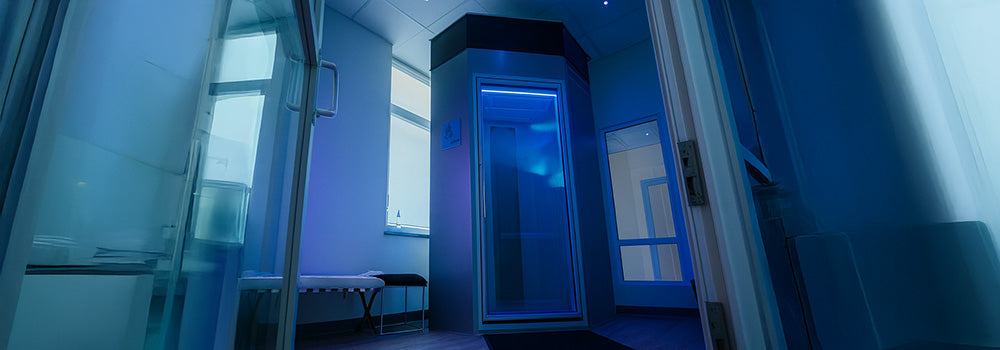 Futuristic cryo chamber in a cool-toned wellness room with blue LED lighting and modern glass walls.