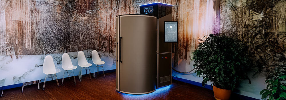 Modern cryotherapy chamber in a warm-toned room with winter forest mural and wood flooring.