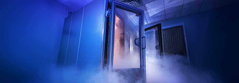 Futuristic cryotherapy chamber with mist and glowing blue-pink lighting in a high-tech room.