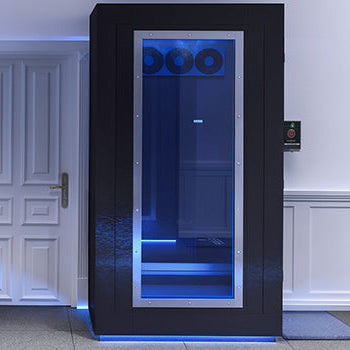 Black cryotherapy chamber with blue-lit interior in a refined wellness room with white paneled walls and modern finishes.