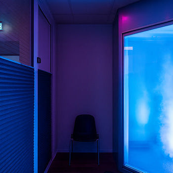 Cryochamber in a futuristic treatment space with glowing blue lights, magenta accents, and sleek interior design.