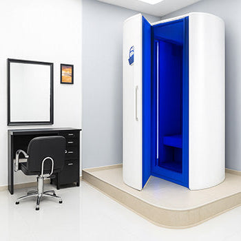 Cryotherapy chamber in a modern beauty clinic with black styling chairs, white tile flooring, and bright LED lighting.