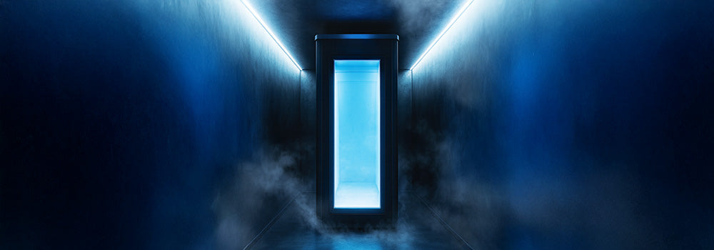 Cryotherapy chamber in a dark hallway with blue LED lighting and swirling cold mist for a futuristic wellness experience.