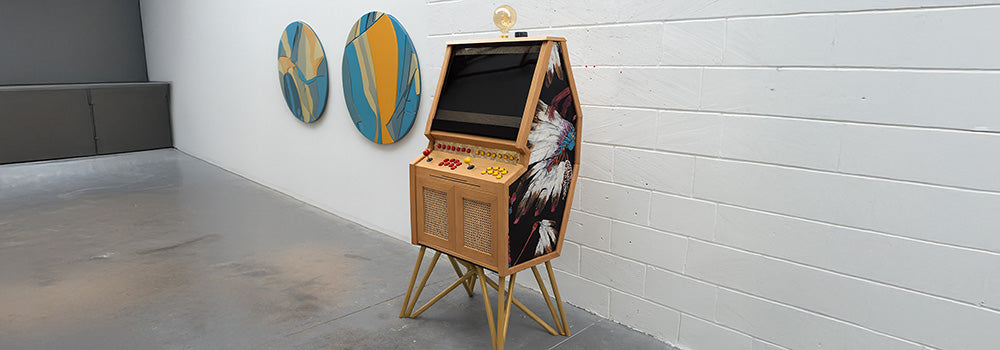 custom wooden arcade machine with Native American feather artwork and golden legs in modern art gallery.