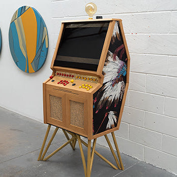 custom wooden arcade machine with Native American feather artwork and golden legs in modern art gallery.