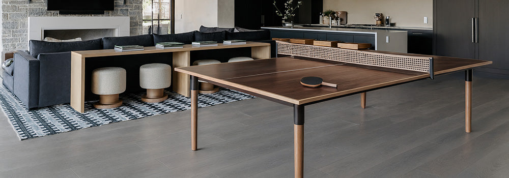 dark wood ping pong table in a modern open-plan kitchen and living room with stone fireplace and designer lighting.