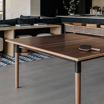 dark wood ping pong table in a modern open-plan kitchen and living room with stone fireplace and designer lighting.