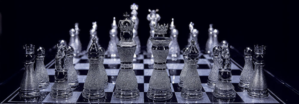 Luxury diamond-encrusted chess set on a glossy black-and-white board under dramatic lighting.