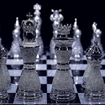 Luxury diamond-encrusted chess set on a glossy black-and-white board under dramatic lighting.