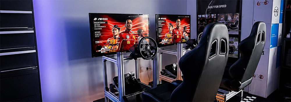 Dual racing simulator gaming setup with racing seats, steering wheels, pedals and monitors for an immersive motorsport gaming experience.
