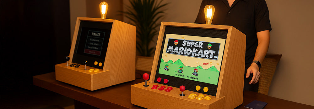 Enhanced wooden arcade machines on a polished table, one showing Super Mario Kart under warm ambient lighting.