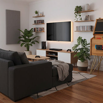 Retro-inspired wooden arcade machine with vibrant side panel artwork, classic joystick controls, and integrated Nintendo Switch console, styled in a modern living room setup with plants and wood flooring.