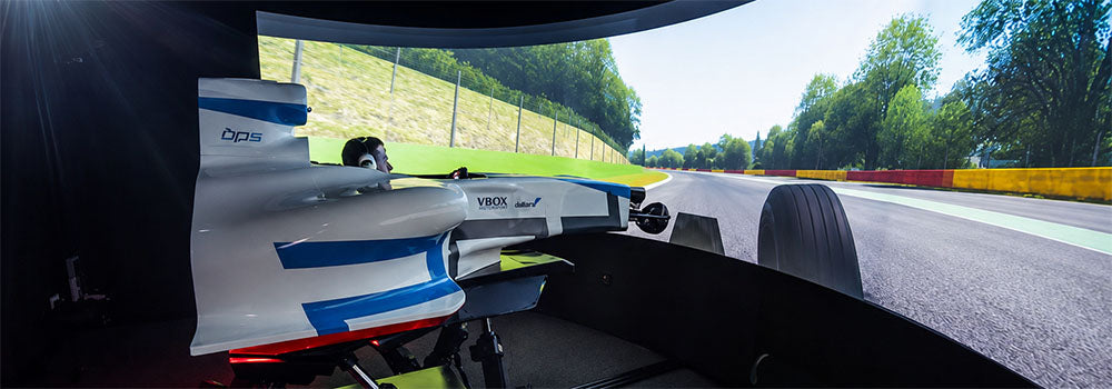 Formula racing simulator with open-wheel cockpit and panoramic curved screen creating an immersive virtual racetrack driving experience.