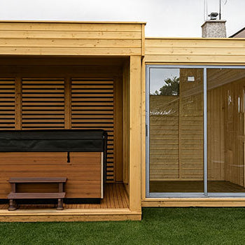 Contemporary garden sauna room with hot tub enclosure and full glass sliding doors on manicured lawn.
