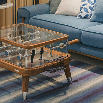 glass-top foosball coffee table with wooden frame in a chic blue living room..