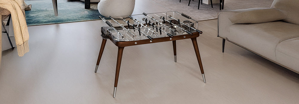 modern glass foosball table with walnut frame in a luxury open-plan living and dining space.