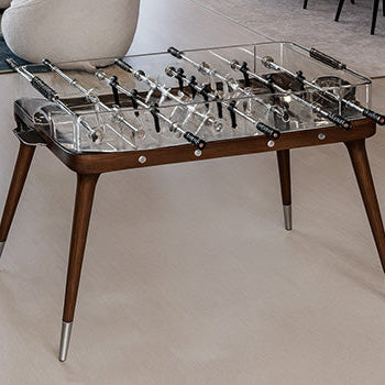 modern glass foosball table with walnut frame in a luxury open-plan living and dining space.