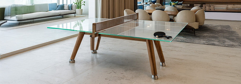 Modern glass ping pong table with wooden legs in bright open-concept living and dining area with neutral tones.