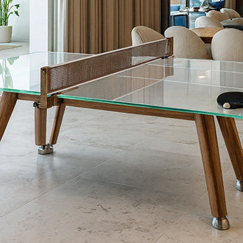 Modern glass ping pong table with wooden legs in bright open-concept living and dining area with neutral tones.