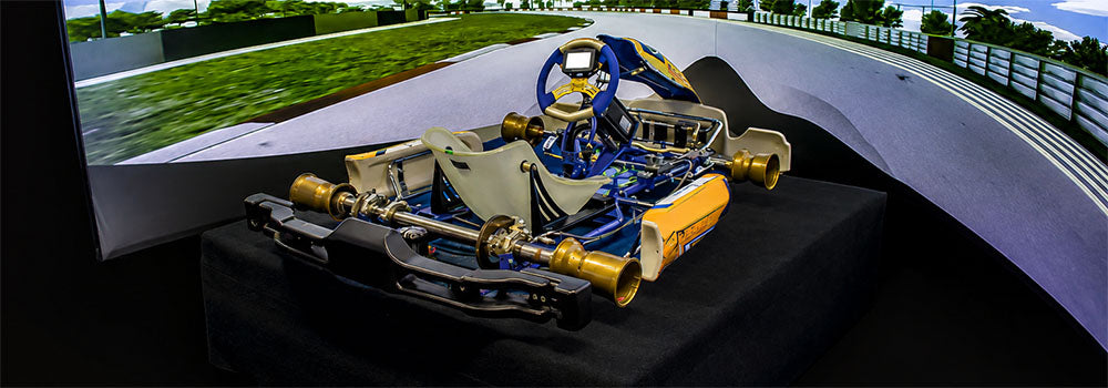 Go-kart racing simulator with realistic kart chassis, steering wheel and panoramic racetrack screen for an immersive karting simulation experience.