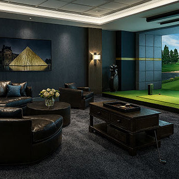 Luxury golf simulator lounge with black leather seating and dark blue walls.