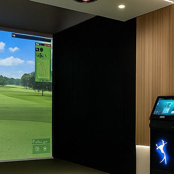 Premium golf simulator room with wood accent wall, touchscreen console, and full club set.