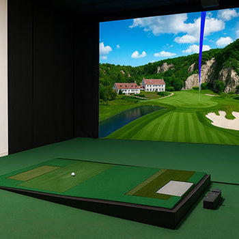 Premium indoor golf simulator with raised hitting mat and projected golf course featuring a villa and cliffside fairway.