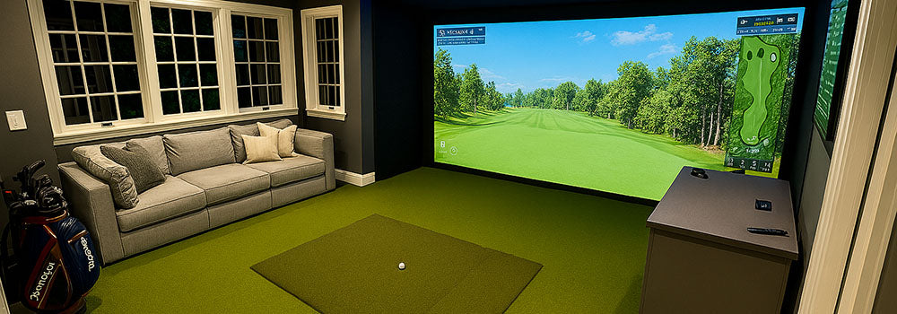 Upscale home golf simulator room with gray sectional, turf flooring, and ambient lighting.