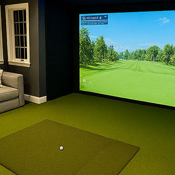 Upscale home golf simulator room with gray sectional, turf flooring, and ambient lighting.