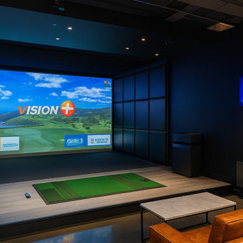 Stylish indoor golf simulator lounge with Vision+ display, leather seating, and dark modern interior.