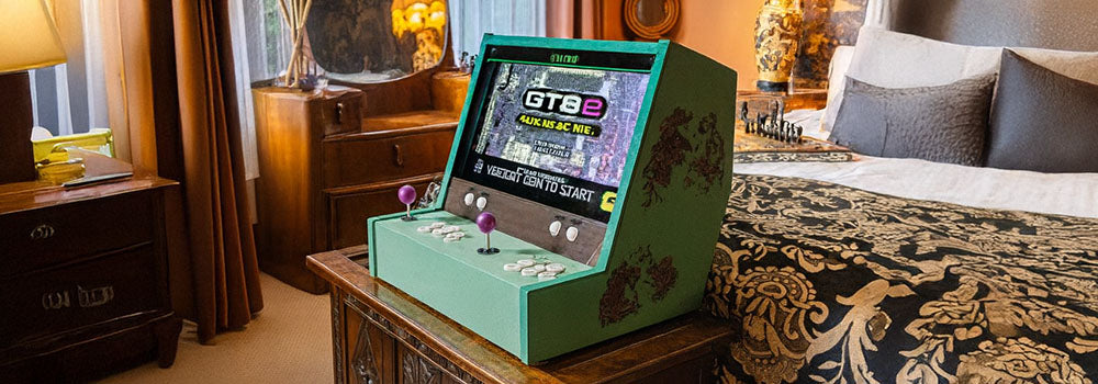 green arcade machine with purple joysticks on a carved wooden chest in a vintage bedroom with ornate furnishings and warm lighting.